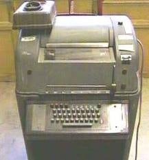 image of an old TTY, tall grey machine with keyboard on front side, and several buttons on top